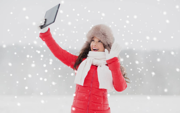 woman in winter fur hat with tablet pc outdoors - Фото, зображення