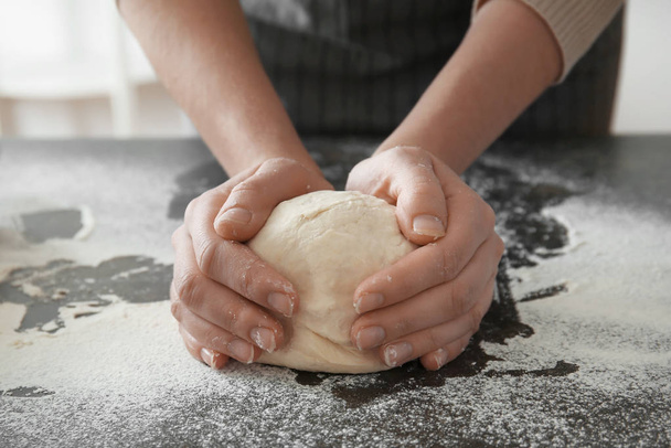 Woman holding dough on table, closeup - Fotografie, Obrázek