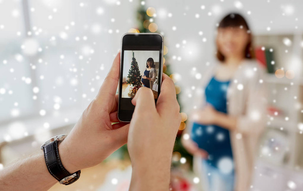 husband photographing pregnant fife at christmas - Foto, Imagen