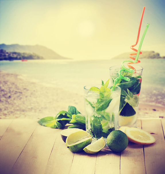 mojito cocktails with straws on wooden table with beach on background - Φωτογραφία, εικόνα