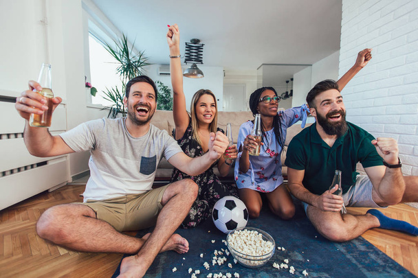 Onnellisia ystäviä tai jalkapallofaneja katsomassa jalkapalloa televisiosta ja juhlimassa voittoa kotona.Ystävyys, urheilu ja viihde käsite. - Valokuva, kuva