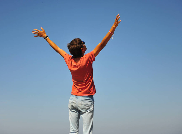 Mladý muž držel ruku volně otevřít s modrou oblohou v pozadí - Fotografie, Obrázek