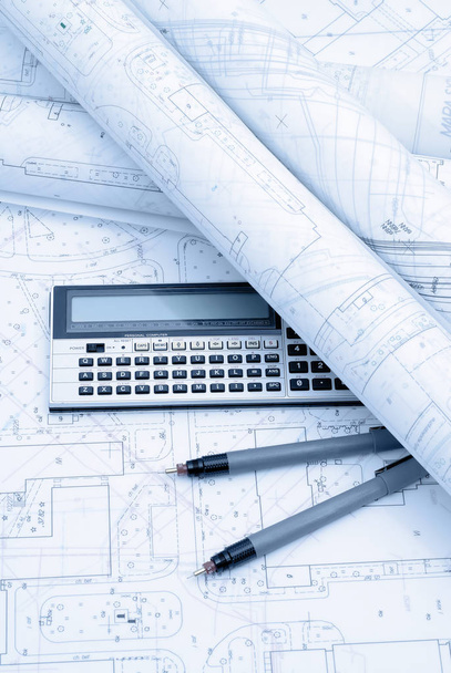 Architectural plans, calculator and drawing utensils. Picture in blue tone. - Photo, Image