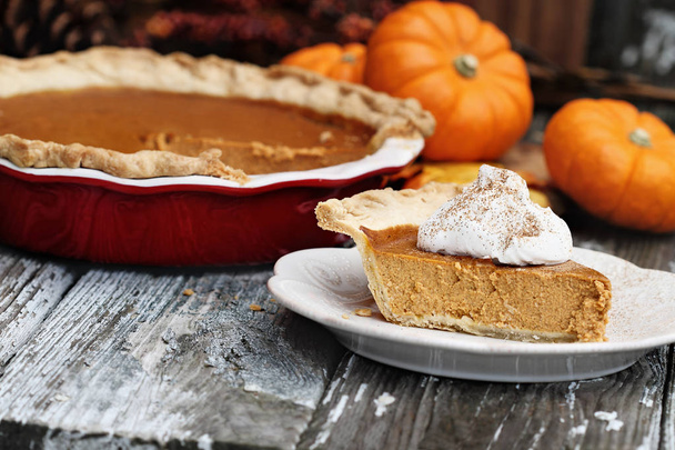 Slice of homemade pumpkin pie over a rustic wooden background. Extreme shallow depth of field with selective focus. - Foto, immagini