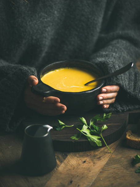 Woman in dark grey woolen winter sweater eating sweet corn and shrimp chowder soup from black bowl - Foto, Imagem