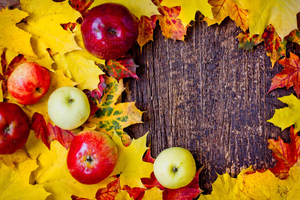 top view of autumn leaves and apples on wooden table - Foto, afbeelding