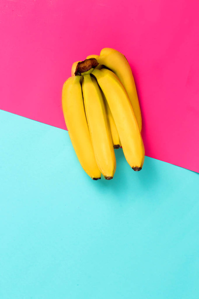Bunch of bananas on blue and pink paper background - Фото, зображення