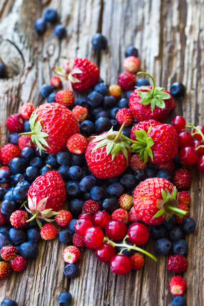 close-up of fresh strawberries, blueberries and red currants in heap on wooden surface - Photo, Image