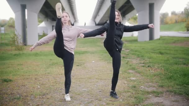 Acrobatische meisjes gaan naar de camera het verhogen van hun benen zeer hoog - Video