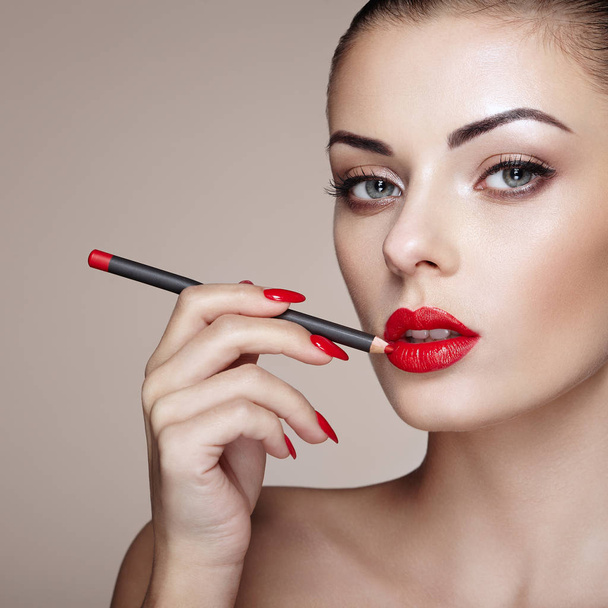Beautiful woman paints lips with lipstick. Beautiful woman face. Makeup detail. Beauty girl with perfect skin - Фото, зображення
