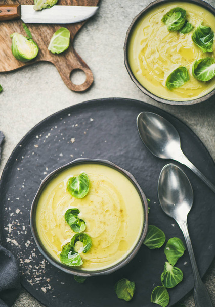 Seasonal brussels sprouts vegetable cream soup in black bowl and fresh green brussel sprouts on wooden board - Фото, зображення