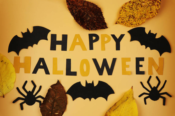 Вид на знак Счастливого Хэллоуина с черными летучими мышами и пауками. Also we can see autumn leaves.Trick or treat. Американский праздник. Оранжевый фон
 - Фото, изображение