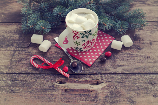 lähikuva kahvikuppi vaahtokarkkeja ja joulukoristeita yli puinen pöytä
 - Valokuva, kuva