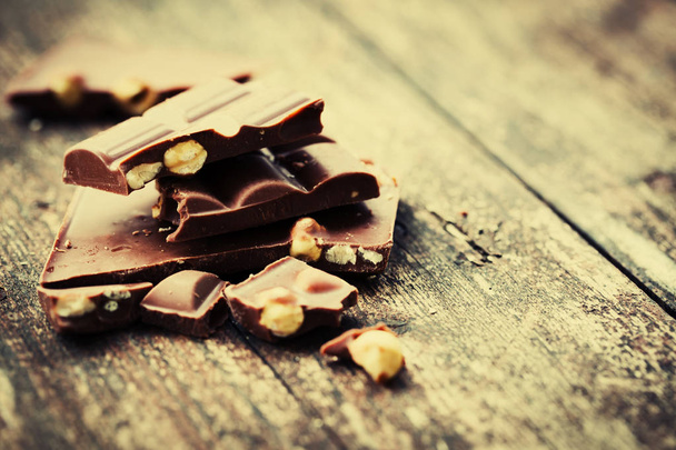 Broken chocolate with nuts on wooden background - Φωτογραφία, εικόνα