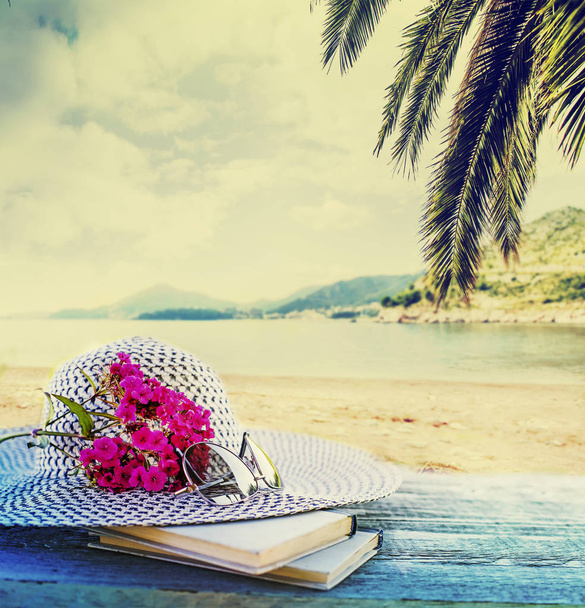 Female hat with glasses, books and pink flowers on blurred nature background - Fotoğraf, Görsel