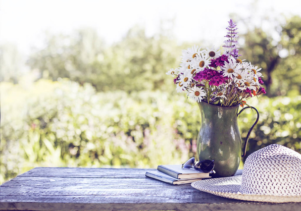 bouquet de fleurs sauvages sur table de jardin en bois avec chapeau
 - Photo, image