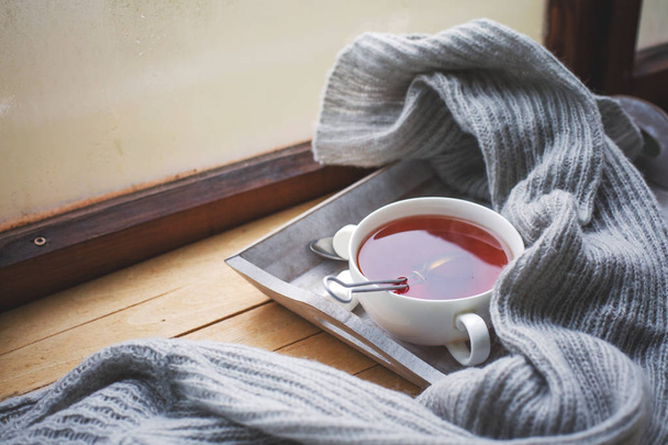 cup of hot tea and scarf on wooden surface - Valokuva, kuva