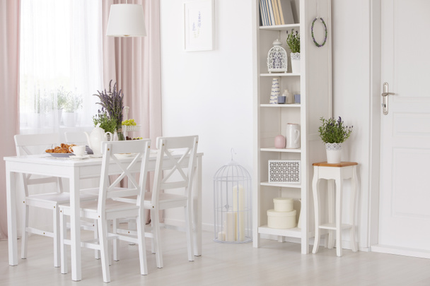 Chaises blanches et table avec des fleurs sous la lampe dans la salle à manger intérieur avec des fleurs de lavande. Une vraie photo
 - Photo, image