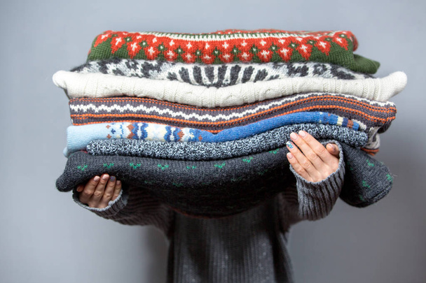 Pile of sweaters on woman hands - Фото, изображение