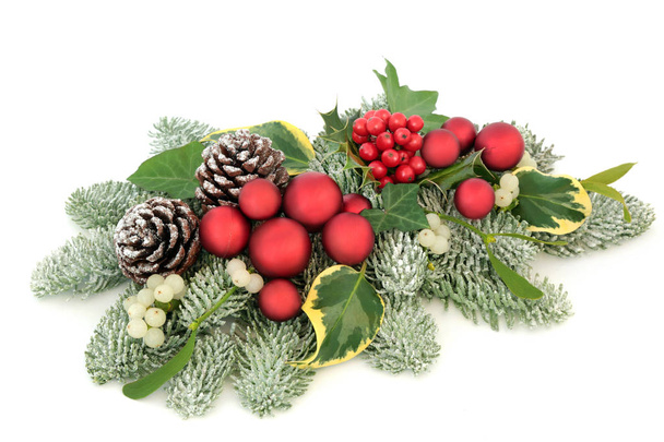 Decoración de mesa navideña con adornos de bolas rojas, bayas de acebo, pino picea cubierto de nieve, hiedra, conos de pino y muérdago aislados sobre fondo blanco
. - Foto, imagen