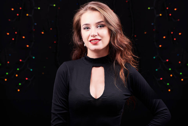Young elegant woman with bright make-up on black background. Christmas and New Year time. - Foto, afbeelding