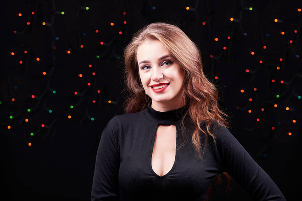 Young elegant woman with bright make-up on black background. Christmas and New Year time. - Foto, imagen