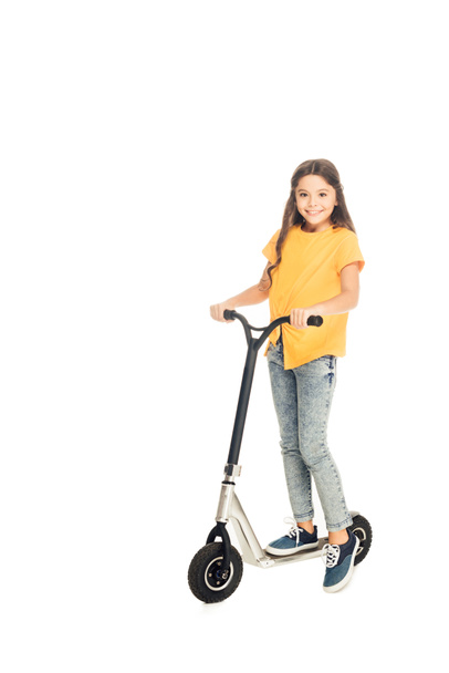adorable happy child riding scooter and smiling at camera isolated on white - Zdjęcie, obraz
