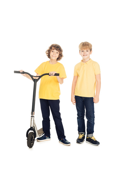 cute happy boys standing with scooter and smiling at camera isolated on white white - Foto, afbeelding
