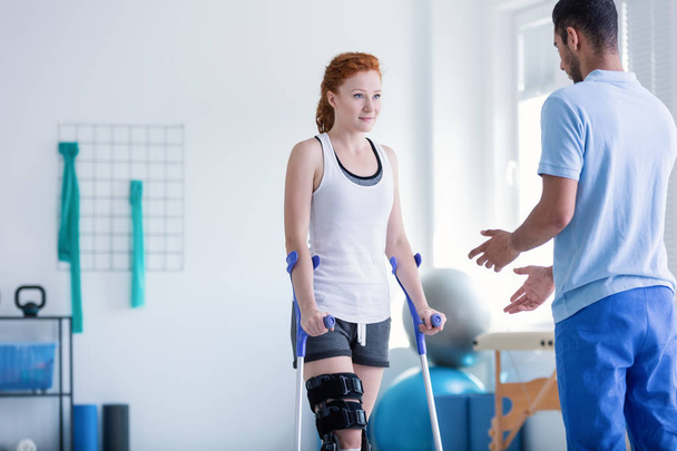 Woman with crutches during rehabilitation with helpful physiotherapist - Fotografie, Obrázek