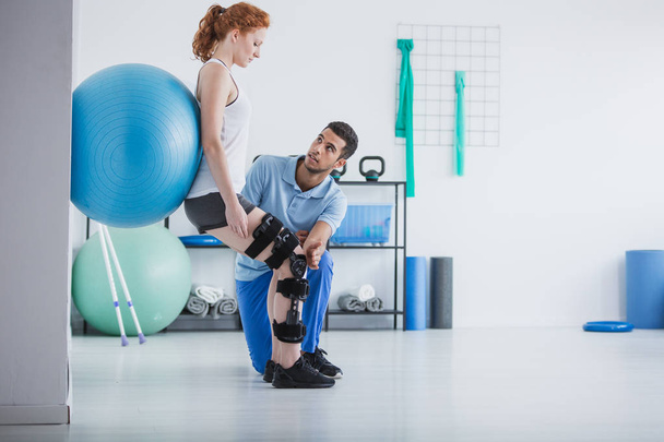 Woman with orthopedic problem exercising with ball while physiotherapist supporting her - Фото, изображение