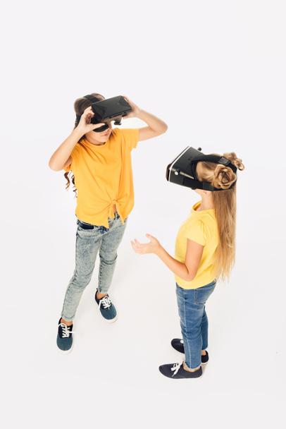 high angle view of beautiful kids using virtual reality headsets isolated on white  - Fotografie, Obrázek