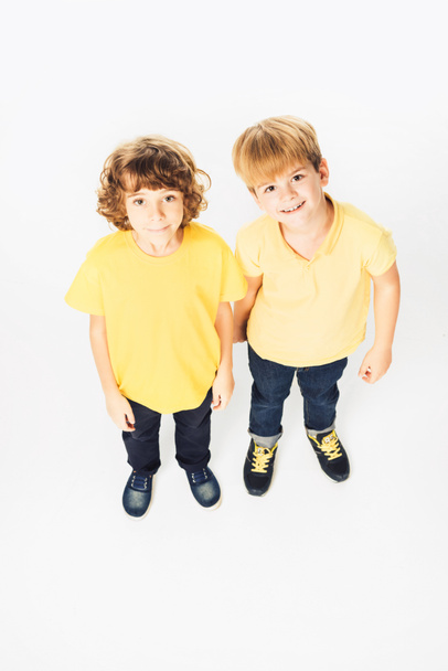 high angle view of two happy boys standing together and smiling at camera isolated on white - Photo, Image