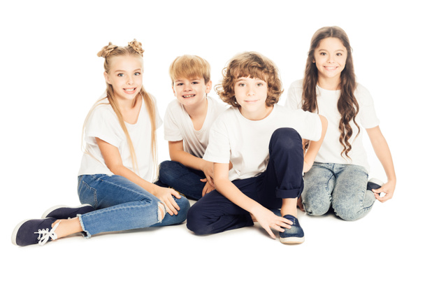 grupo de belas crianças felizes sentadas juntas e sorrindo para a câmera isolada no branco
 - Foto, Imagem