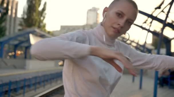 extraordinary caucasian woman dancer is performing loose in sunlight while train is coming outside - Filmati, video