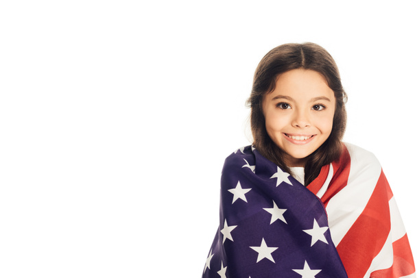 niño adorable sonriente envuelto en bandera americana mirando la cámara aislada en blanco
 - Foto, imagen