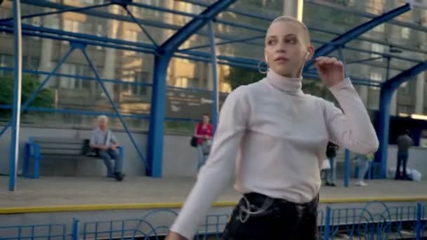 gorgeous calm caucasian blond bald girl is dancing with passion on railway station in summer time with train on background - Záběry, video