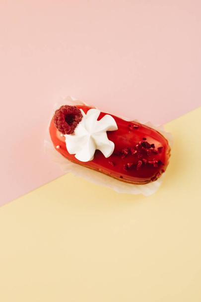 leckeres Eclair mit roter Glasur und Himbeere, süßes Dessert  - Foto, Bild