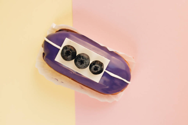 delicious eclair with violet glaze and bluberries, sweet dessert  - Valokuva, kuva