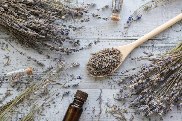 natural dry lavender flowers in big spoon and organic lavender oil over wooden background - Fotografie, Obrázek