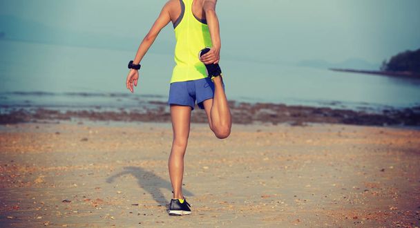 Young fitness woman warming up on sandy beach - Zdjęcie, obraz