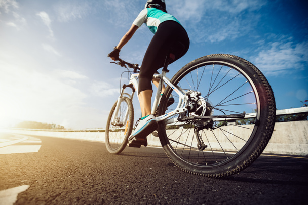 Young woman cyclist riding mountain bike on highway - Foto, Bild