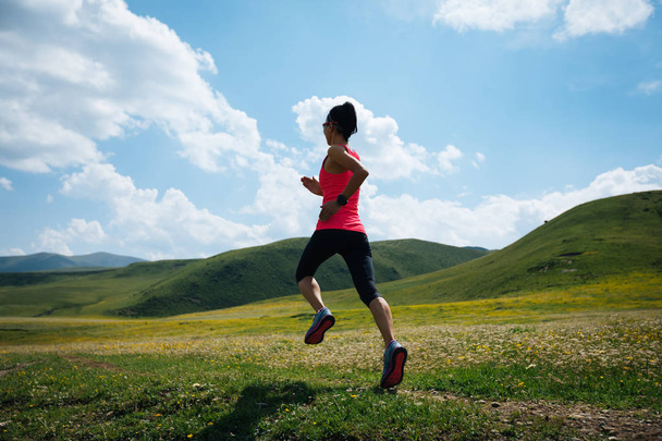Corredor de senderos mujer fitness joven corriendo en los pastizales
 - Foto, Imagen