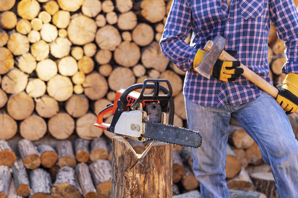 The worker works with a chainsaw. Chainsaw close up. Woodcutter saws tree with chainsaw on sawmill. Chainsaw in action cutting wood. Man cutting wood with saw, dust and movements. - Photo, Image