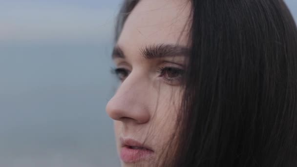 Bir genç kadının yüzü büyük close-up. Model bulanık deniz arka planı standları - Video, Çekim