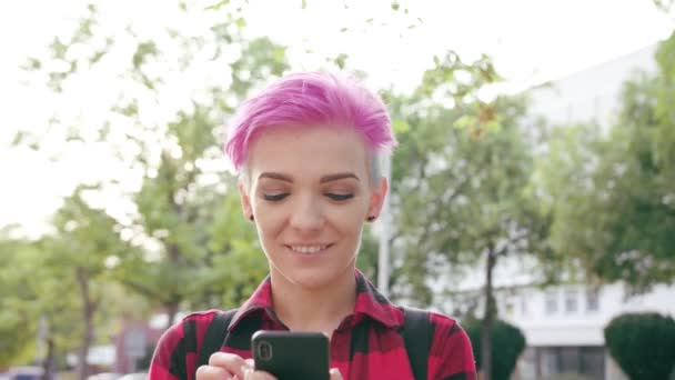 Mulher com cabelo curto rosa usando um telefone na cidade
 - Filmagem, Vídeo