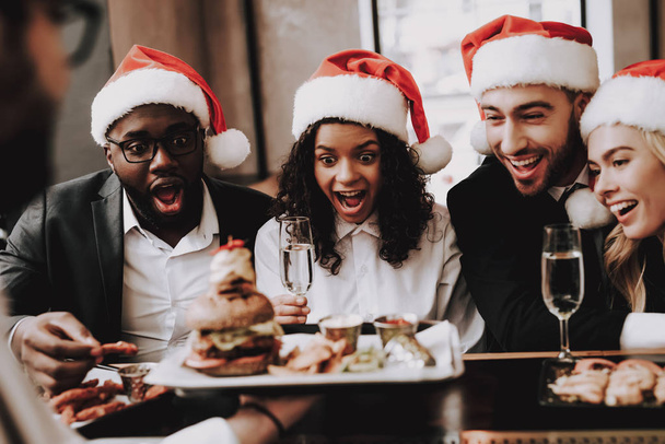 Burger. Santa's Hat. Girls and Guys. Young People. Rest. Drink Alcoholic Beverages. Different Races Communicate. Bar. Have Fun. Together. Clubbing. Nightlife. Joyful. Leisure. Positive. Emotion. - Foto, afbeelding