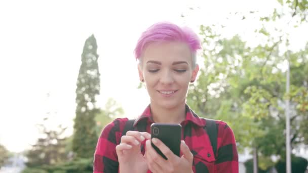 Mujer con el pelo corto rosa usando un teléfono en la ciudad
 - Metraje, vídeo