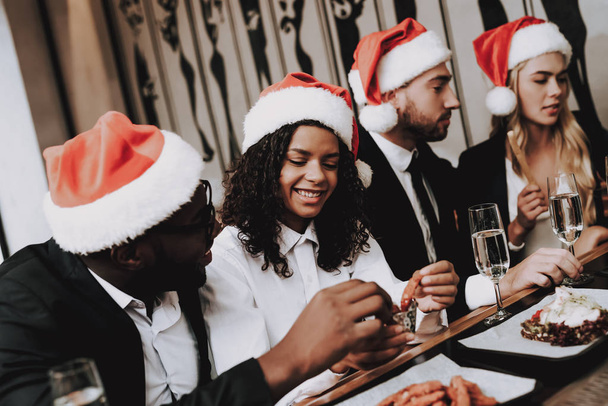 Santa's Hat. Different Races Communicate. Young People. Rest. Girls and Guys. Drink Alcoholic Beverages. Bar. Have Fun. Together. Clubbing. Nightlife. Joyful. Chin-chin. Leisure. Positive. Emotion. - Foto, Imagen