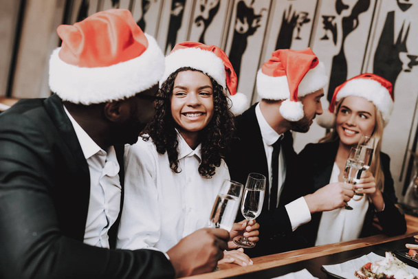 Santa's Hat. Leisure. Young People. Rest. Girls and Guys. Drink Alcoholic Beverages. Different Races Communicate. Bar. Have Fun. Together. Clubbing. Nightlife. Joyful. Chin-chin. Positive. Emotion. - Φωτογραφία, εικόνα