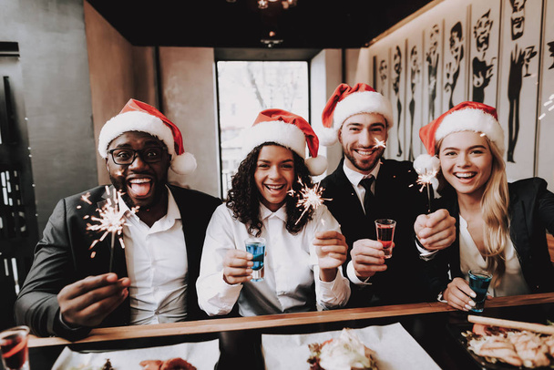 Santa's Hat. Young People. Rest. Girls and Guys. Drink Alcoholic Beverages. Different Races Communicate. Bar. Have Fun. Together. Clubbing. Nightlife. Joyful. Chin-chin. Leisure. Positive. Emotion. - Photo, image